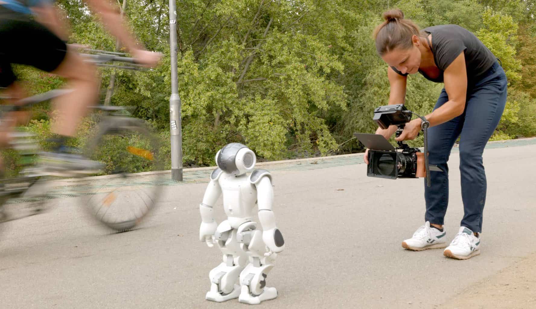 Person filmt einen etwa 50 cm hohen Roboter, der auf sie zufäuft